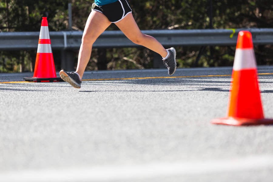 Lower Section of a Marathon Runner Running on a Road
