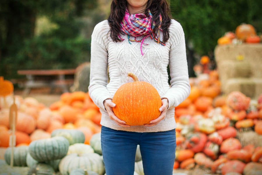 Woman Holding a Pumpkin at a Farm