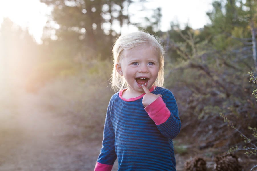 Silly Toddler Girl Standing on a Trail in Nature and Smiling