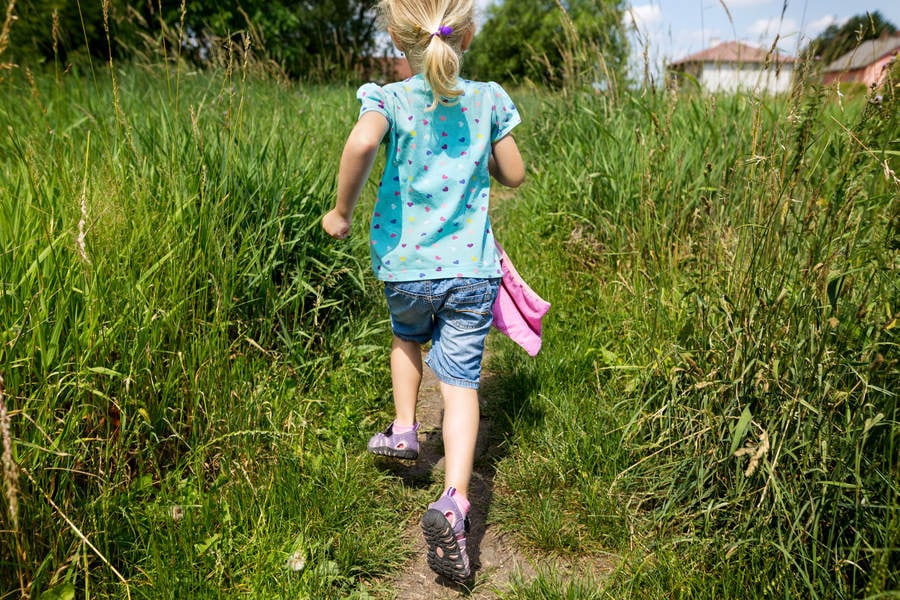 Little Joyful Girl Running on a Trail Through Tall Grass