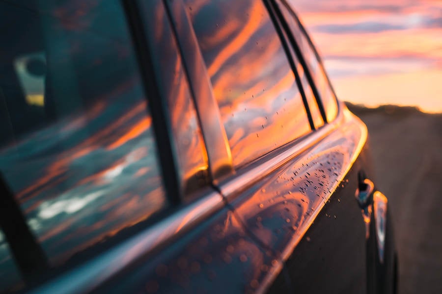 Car Door with Sunset Sun Reflection and Water Droplets