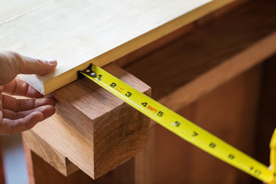 Close-Up of a Handyman Using a Measuring Tape for His Woodworking Project