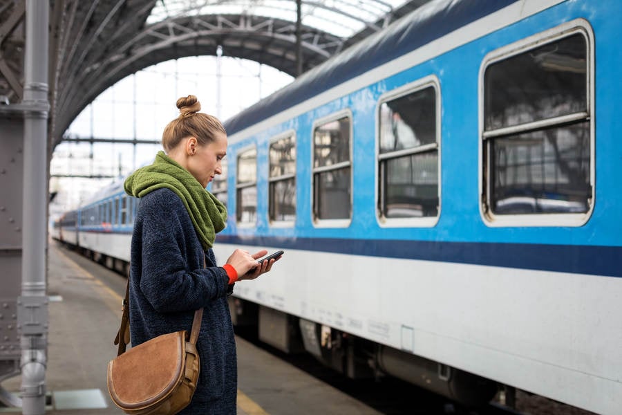 Woman with a Cell Phone Standing on a Railway Platform