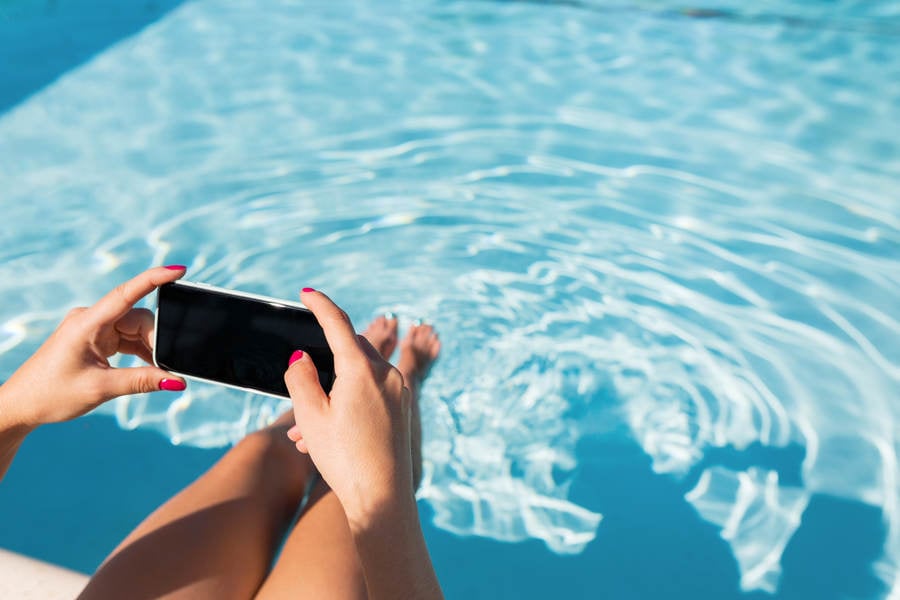 Close-Up of a Woman by Pool Taking Pictures with a Smartphone