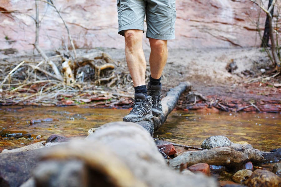 Man Walking on a Log While Crossing a Creek