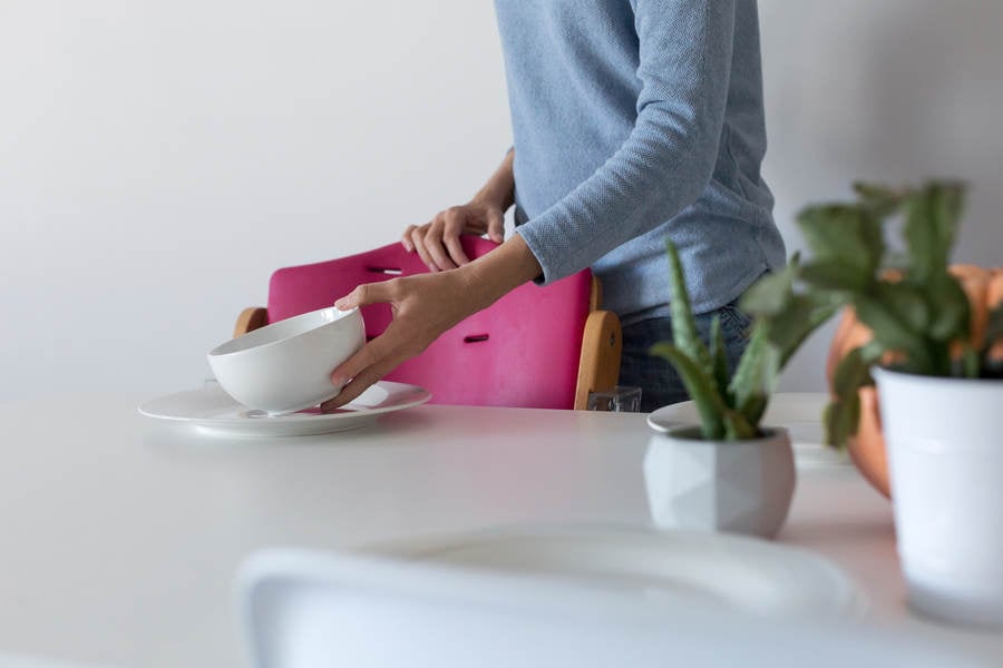 Woman Placing White Bowl on a Dining Room Table at Home