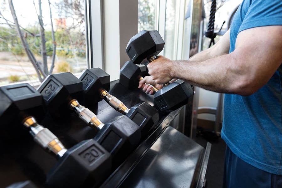 Muscular Man Taking Dumbbells from a Rack in a Gym