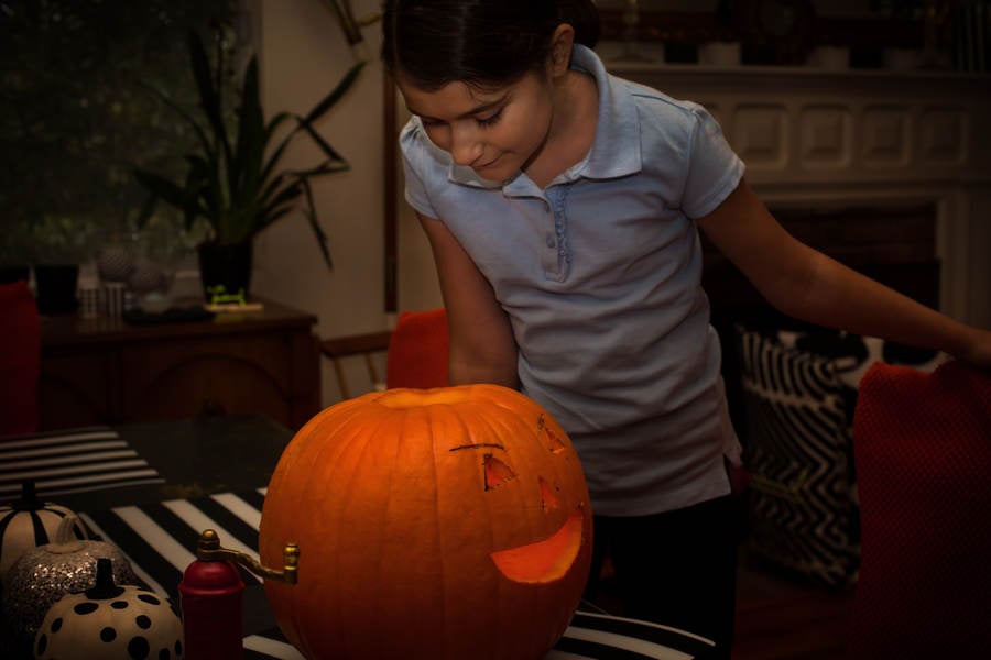 Girl Looking Inside an Illuminated Carved Pumpkin