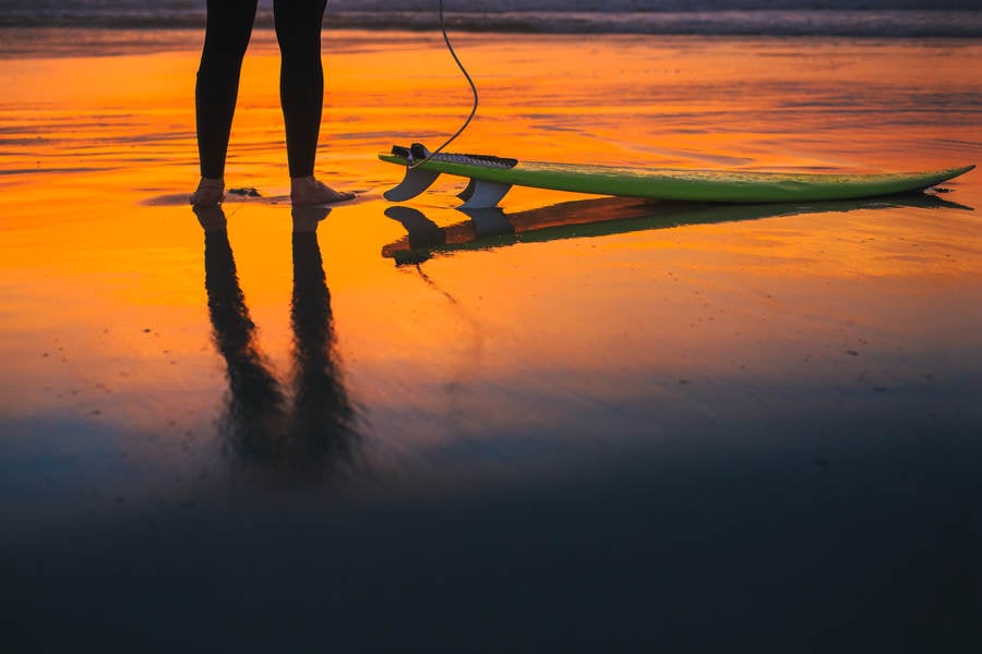 Reflection of a Surfer on a Beach During Sunset
