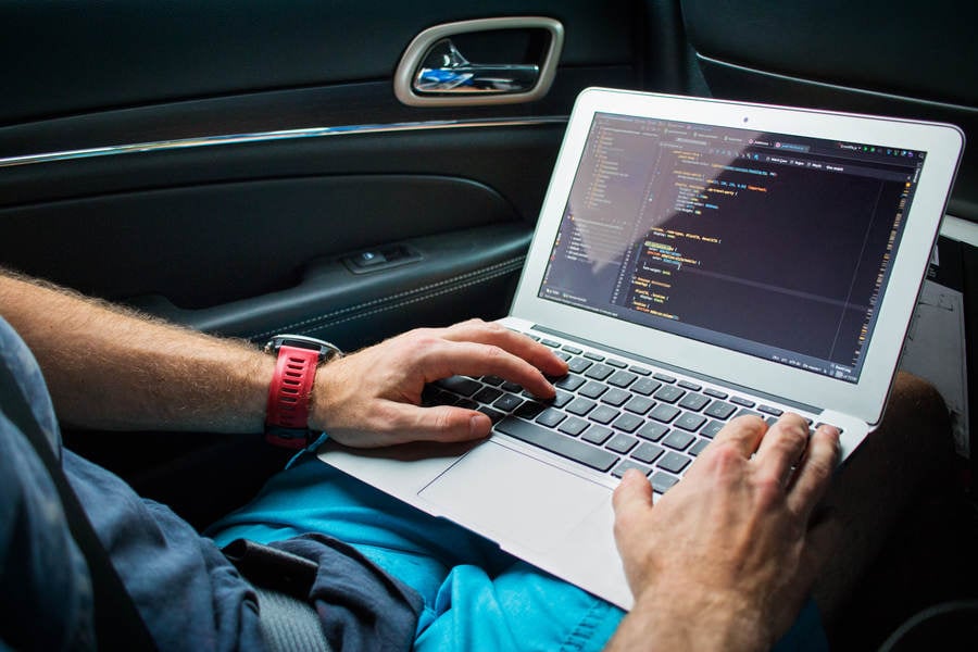 Man Working Remotely on a Laptop While Traveling as a Passenger in a Car