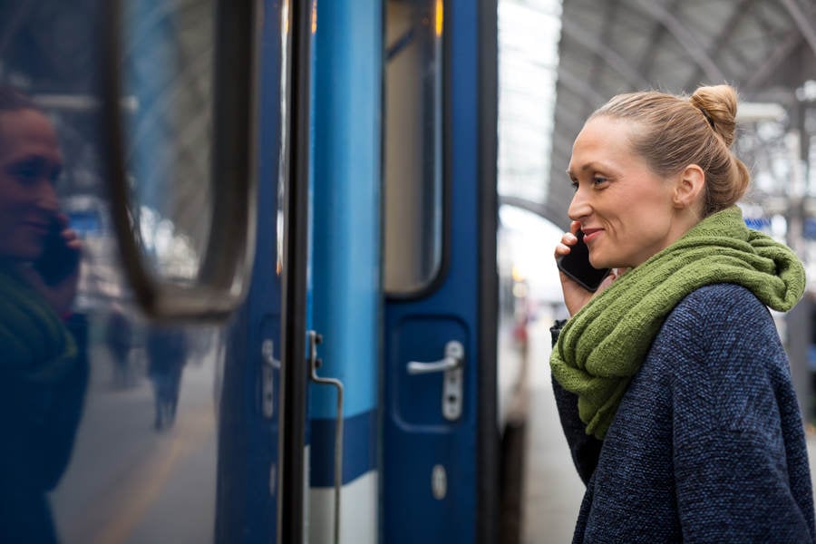 Woman Boarding a Train and Holding a Phone