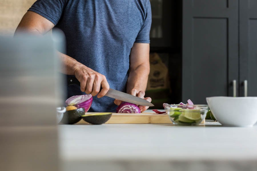 Man Chopping an Onion on a Cutting Board in a Kitchen