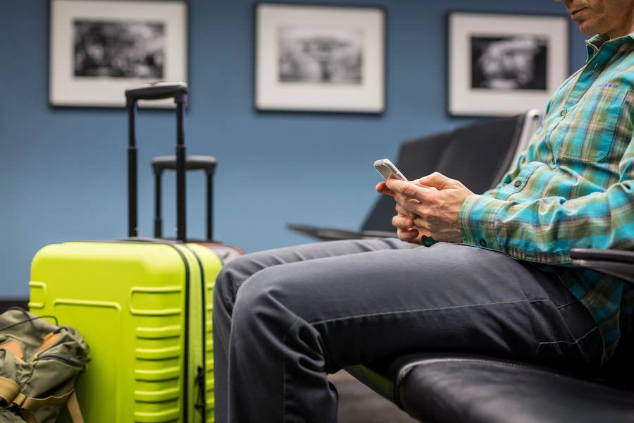 Man Waiting at an Airport Lounge and Using His Cell Phone