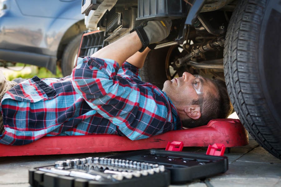 Auto Mechanic Working Underneath the Front of a Truck