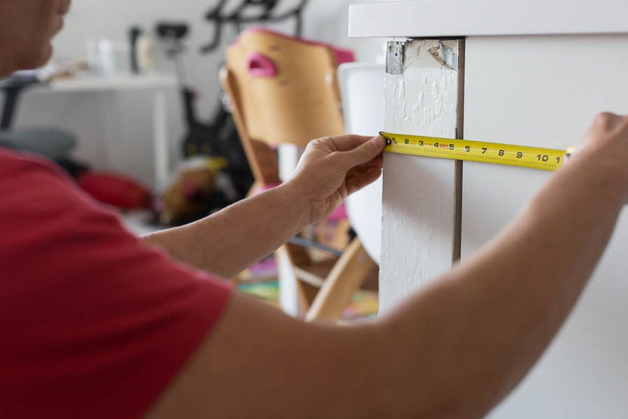 Man Measuring Kitchen Cabinet with a Tape Measure