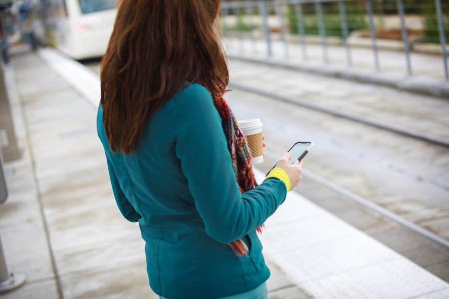 Detailed View of a Woman Looking at Her Phone While Waiting for a Train to Arrive