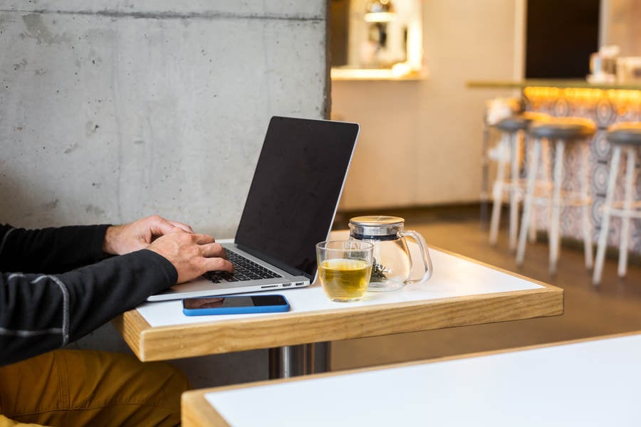 Web Developer Working Remotely on a Laptop in a Trendy Cafe