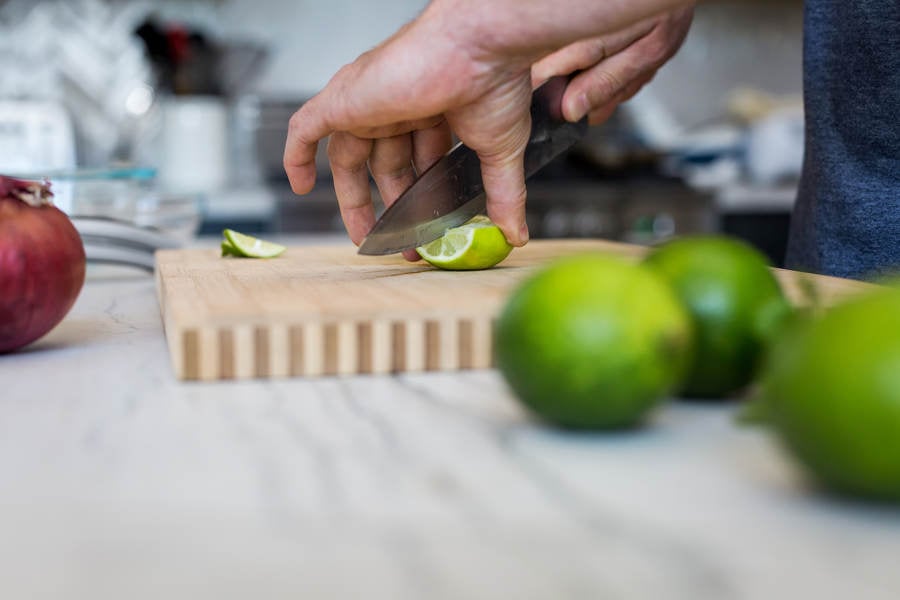 Low-Angle View of a Man Cutting Lime on a Cutting Board