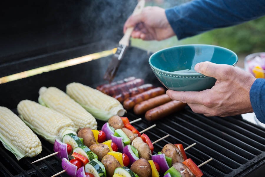 Man Braising Sausages on a BBQ Grill with a Brush