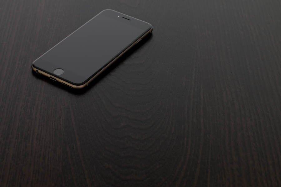 High-Angle View of a Black Cell Phone on a Wooden Table