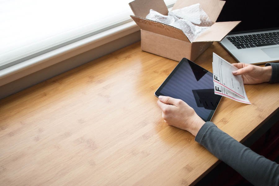 Woman Holding a Tablet in Her Hand While Preparing Shipping Labels