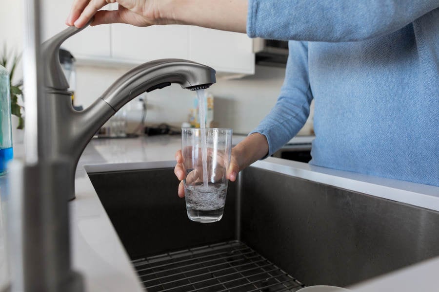 Woman Filling a Glass with Tap Water in a Modern Kitchen