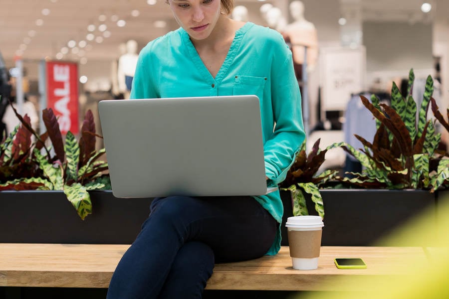 Woman Working on a Laptop in a Shopping Mall