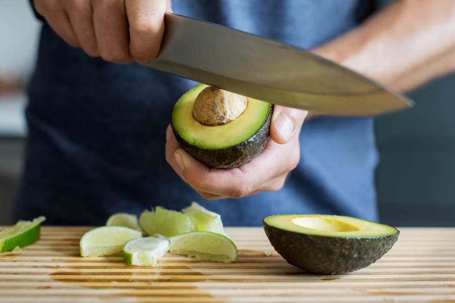 Man Removing a Pit from an Avocado with a Knife