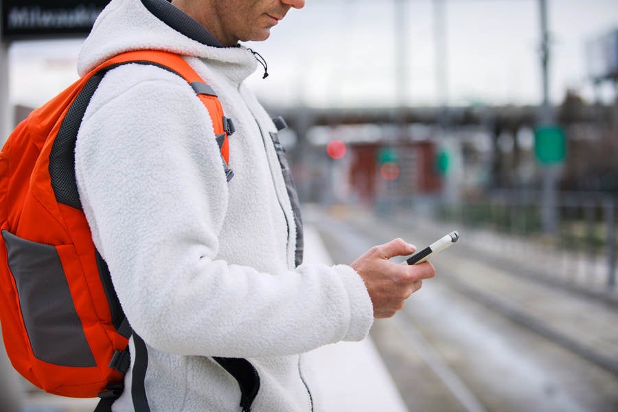 Side-View of a Man Standing on a Train Platform and Checking His Phone
