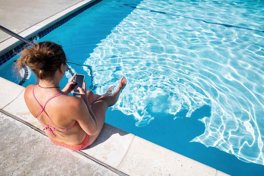 Woman in Bikini Relaxing by Pool and Browsing on a Smartphone