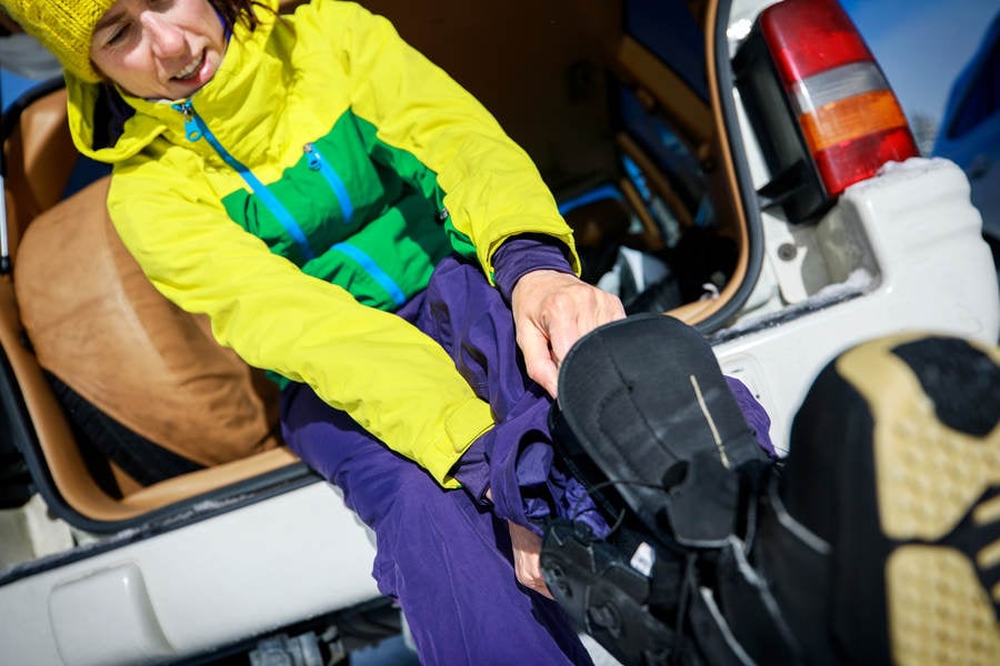 Woman Putting on Snowboarding Boots at the Back of a Car