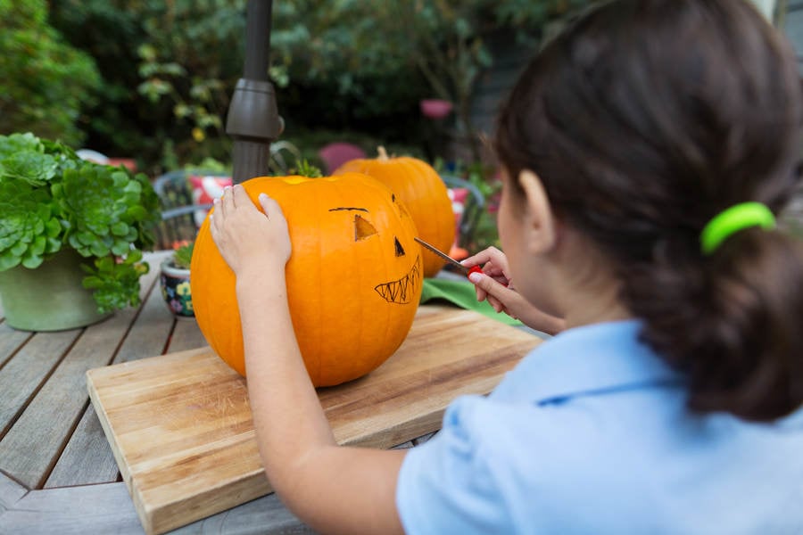 Young Girl Carving a Pumpkin on a Patio