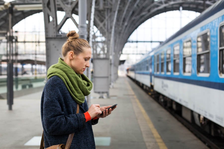 Woman with a Smartphone Standing on a Railway Platform