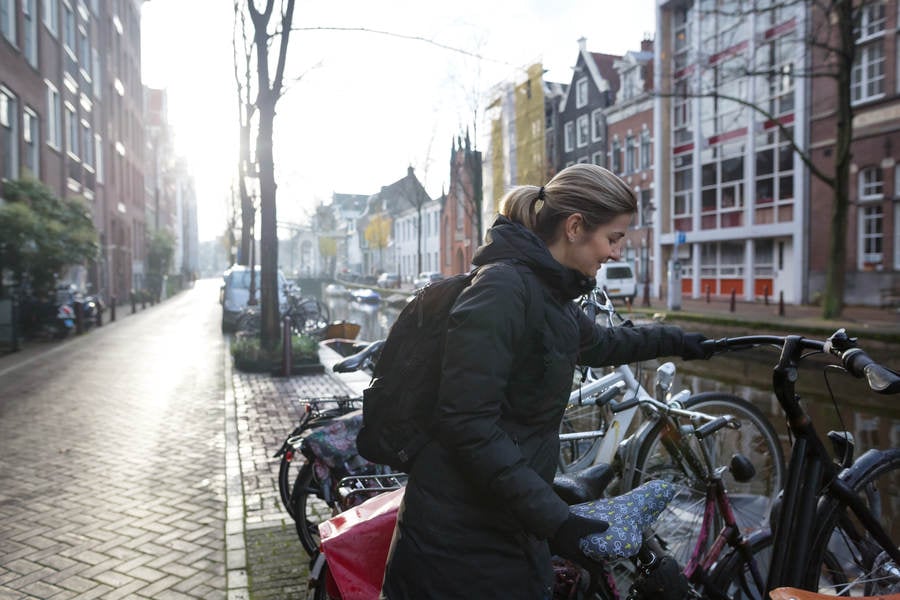 Young Woman Parking a Bicycle by a Canal in Amsterdam