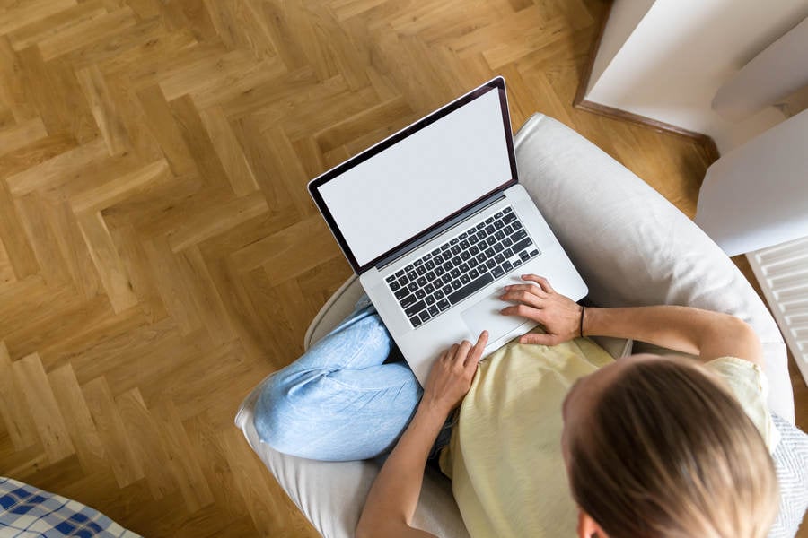 Overhead View of a Young Woman in Casual Clothing Working on a Laptop from Home