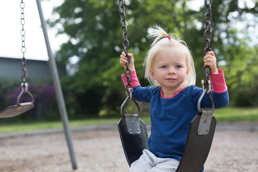 Toddler Girl Sitting on a Swing at Playground