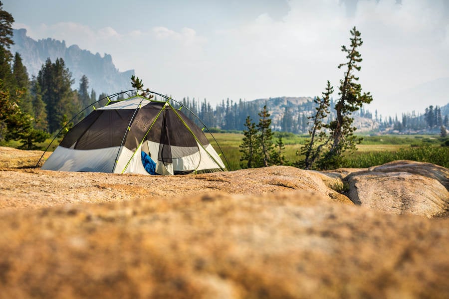 Camping Tent Pitched on a Rock by an Alpine Meadow