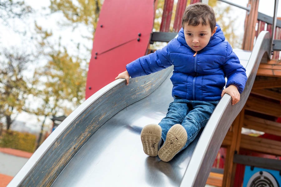 Little Boy Sliding down a Slide at a Playground