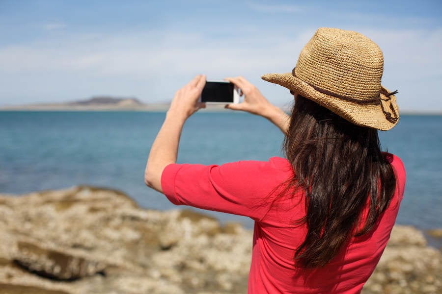 Girl in a Straw Hat Taking a Picture with Her Phone at a Travel Destination