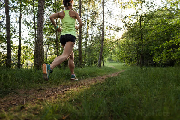 Athletic Woman Running on a Forest Trail During Sunset