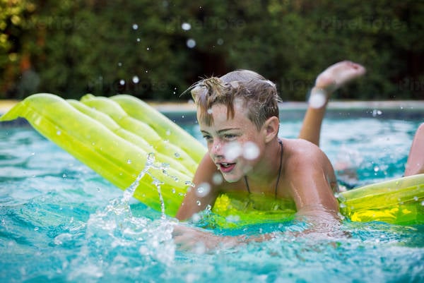 Teenage Boy on an Inflatable Floating Mattress in a Swimming Pool