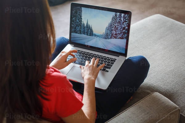 Woman Sitting on a Sofa in a Living Room and Working on a Laptop