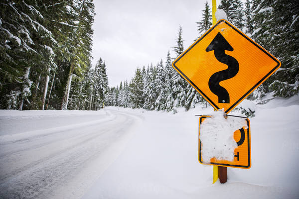 Snowy Mountain Road with a Winding Road Sign