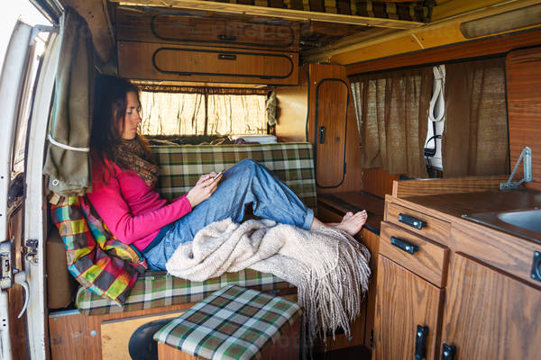 Young Woman in a Camper Van Using a Smartphone