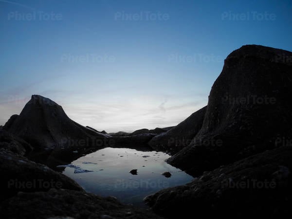 Ground-Level View of a Tidal Pool with an Evening Sky