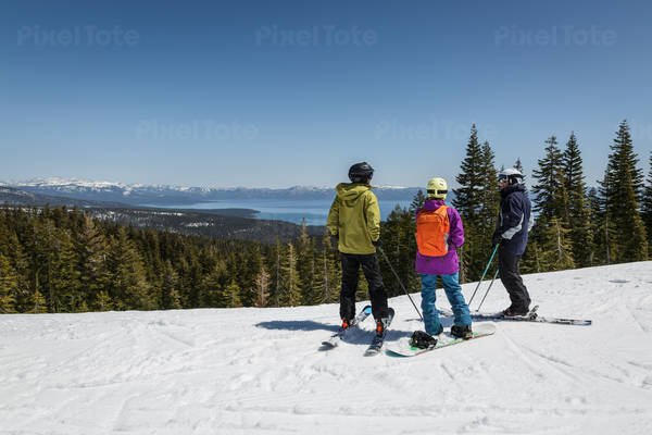 Two Skiers and a Snowboarder at a Sunny Scenic Mountain Ski Resort