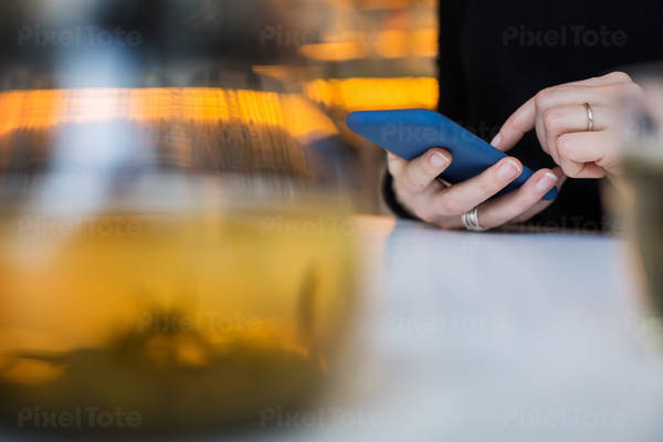 Close-Up View of Hands of a Woman Using a Cell Phone in a Cafe