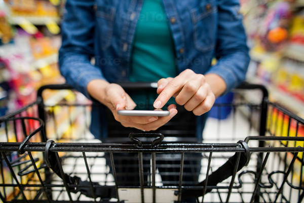 Close-Up of Woman Researching Information on a Cell Phone While Grocery Shopping