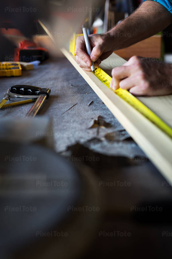 Handyman Measuring a Wooden Plank Before Cutting It with a Mitter Saw