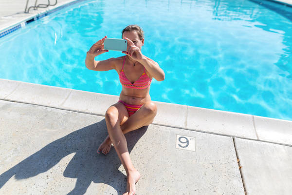 Woman in Bikini Sitting by Pool and Taking a Selfie